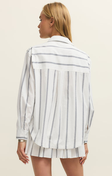 Woman wearing a white and gray striped shirt with a plain background