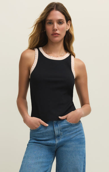 Woman wearing a black tank top with lace trim and blue jeans on a plain background