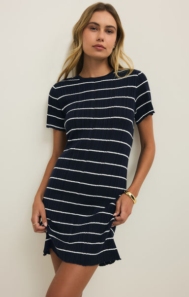Woman wearing a navy and white striped dress against a plain background