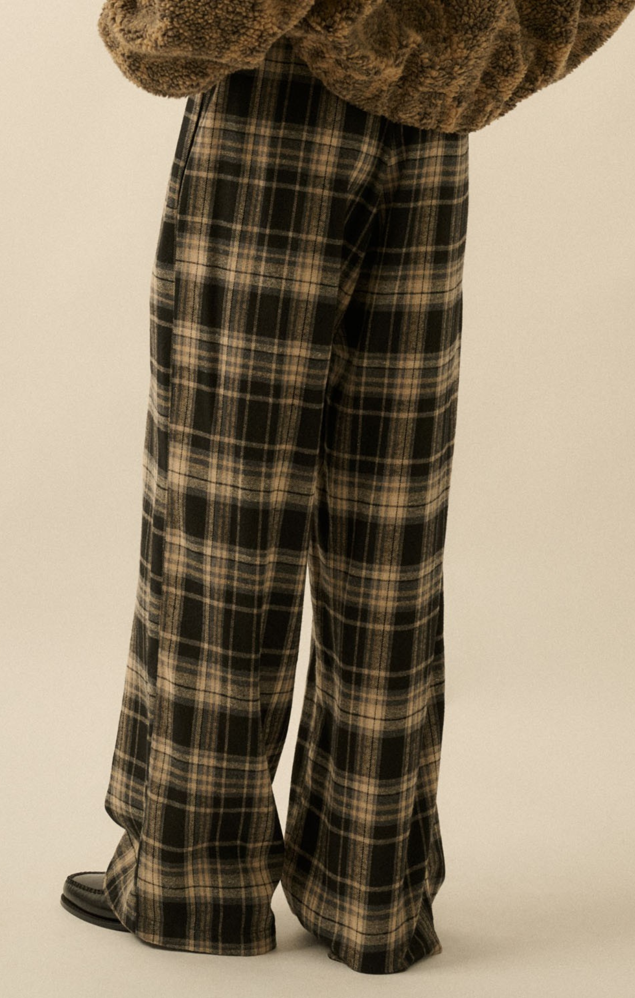 Plaid pants worn by a person on a beige background