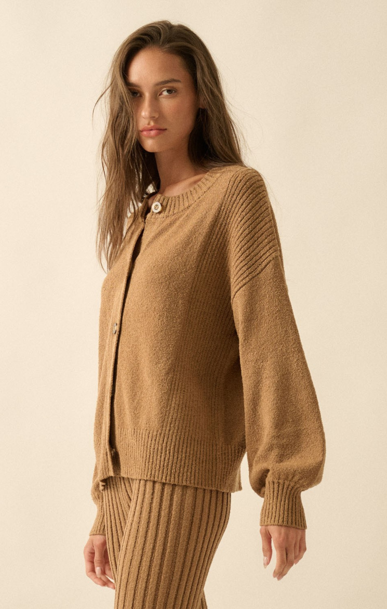 Woman wearing a brown knit cardigan and skirt on a beige background