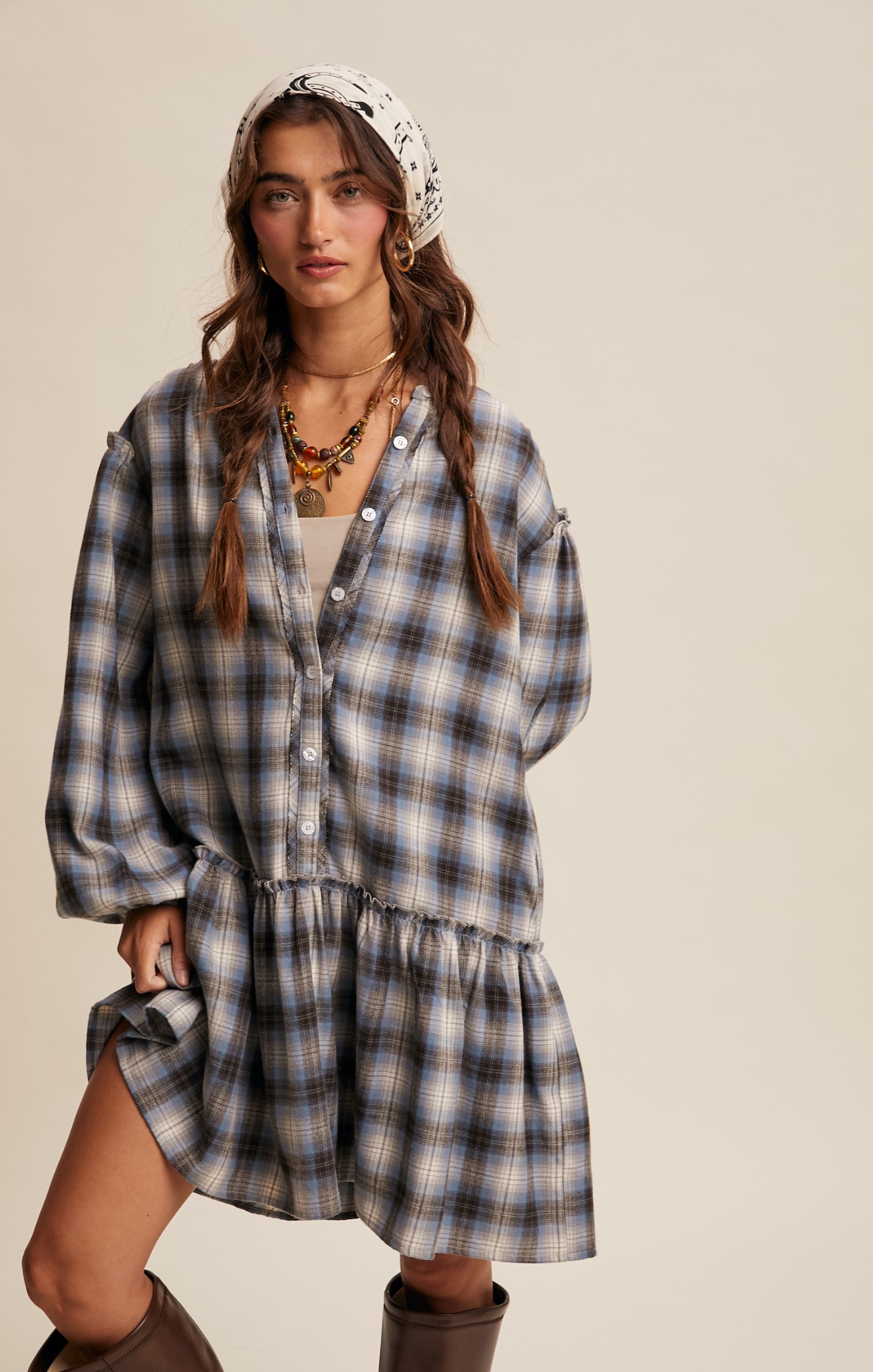 Woman wearing a plaid dress with a headscarf on a beige background