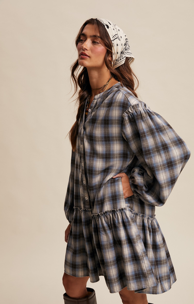 Woman wearing a plaid dress with a headscarf on a beige background