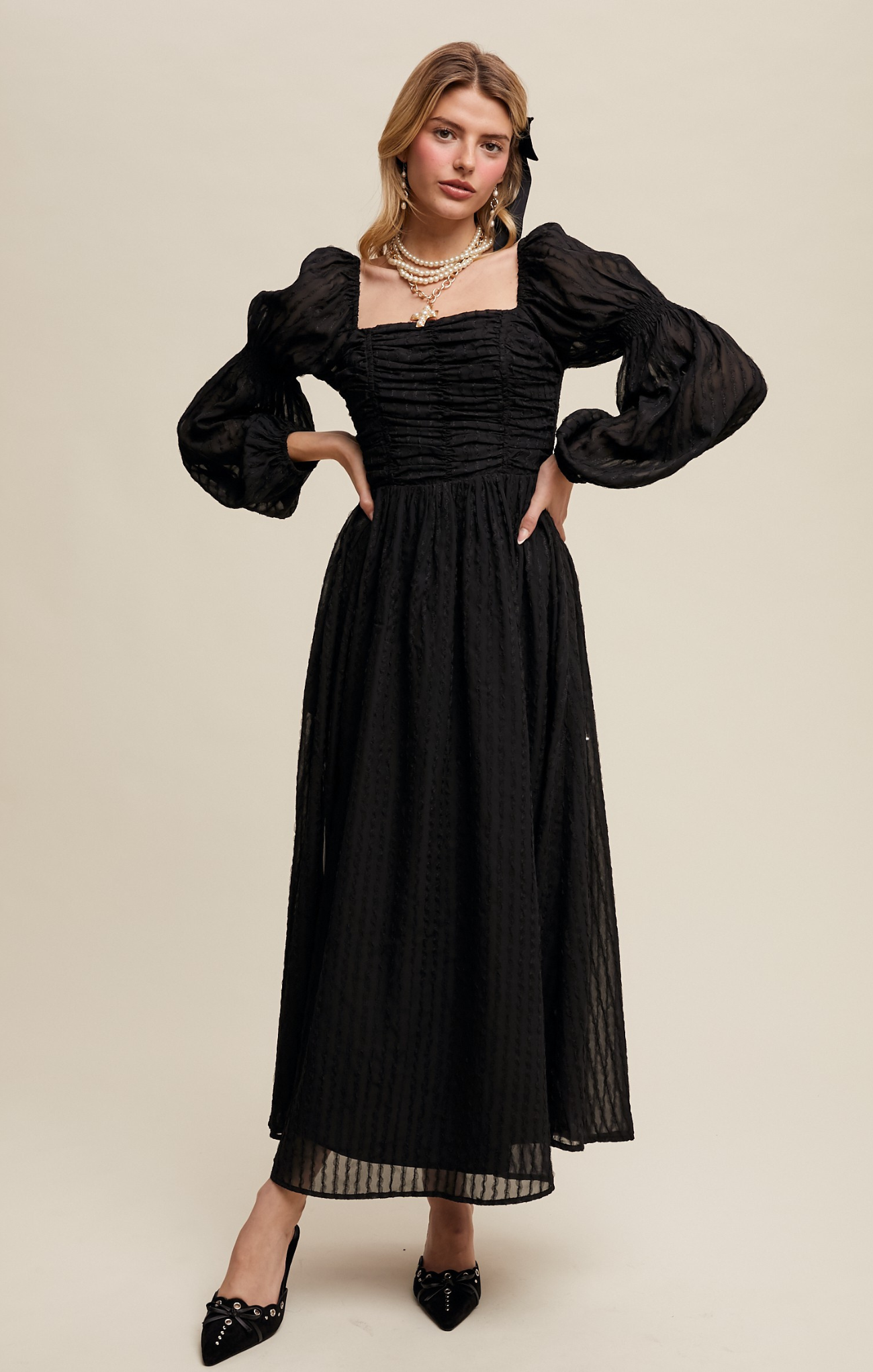 Woman wearing a black dress with puffed sleeves on a beige background