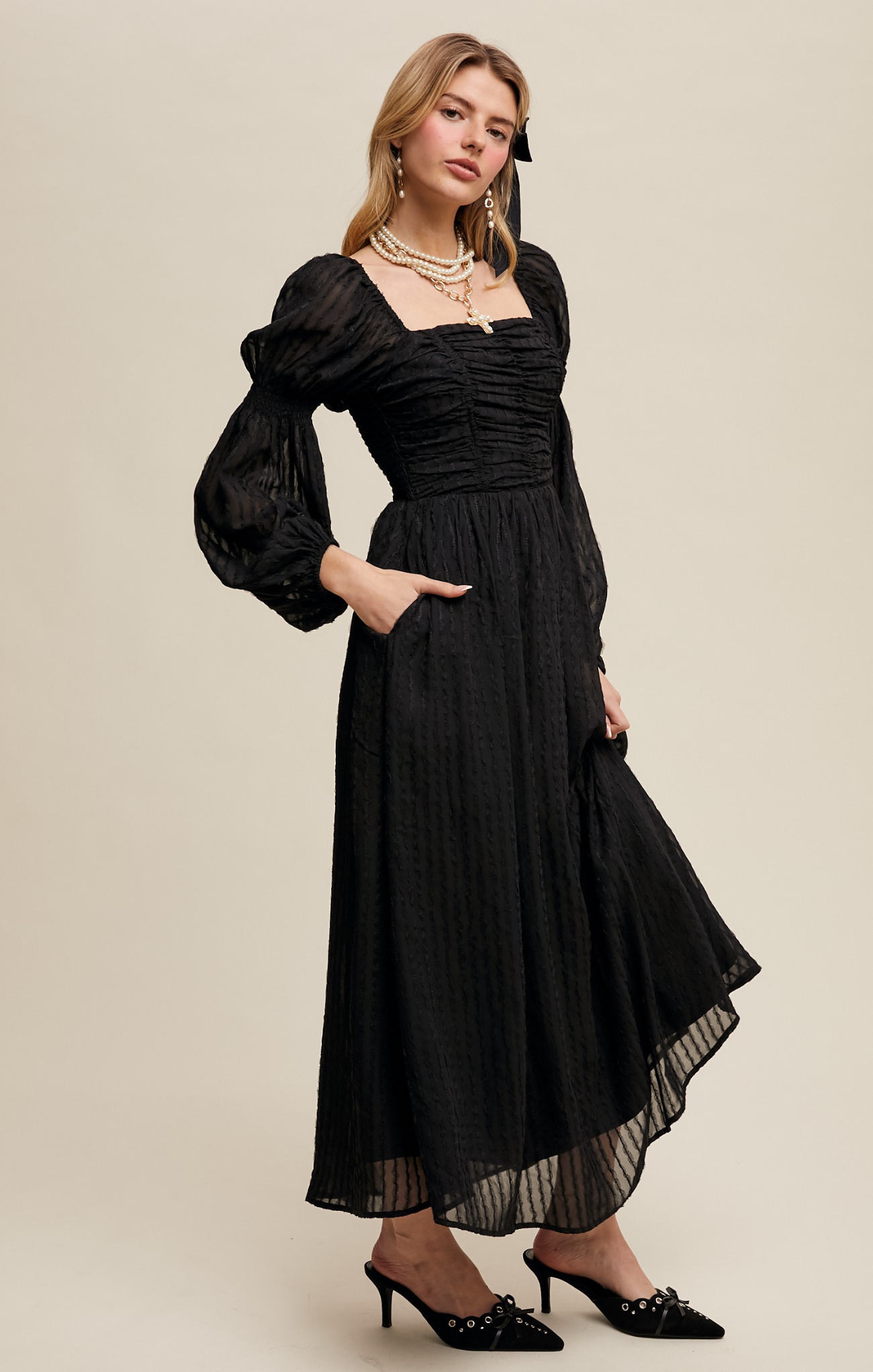 Woman wearing a black dress with puffed sleeves on a beige background