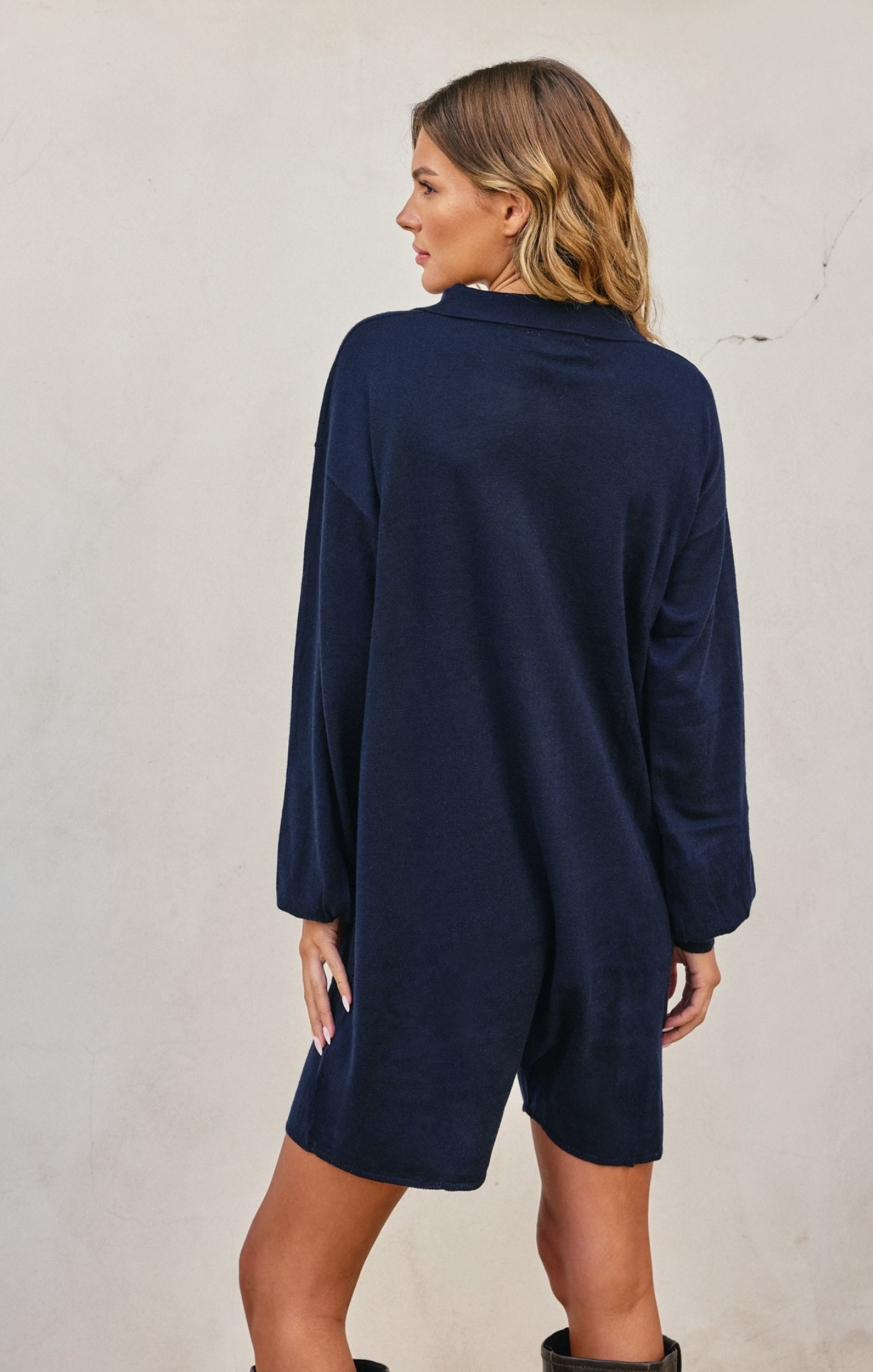 Woman wearing a navy blue dress against a plain background