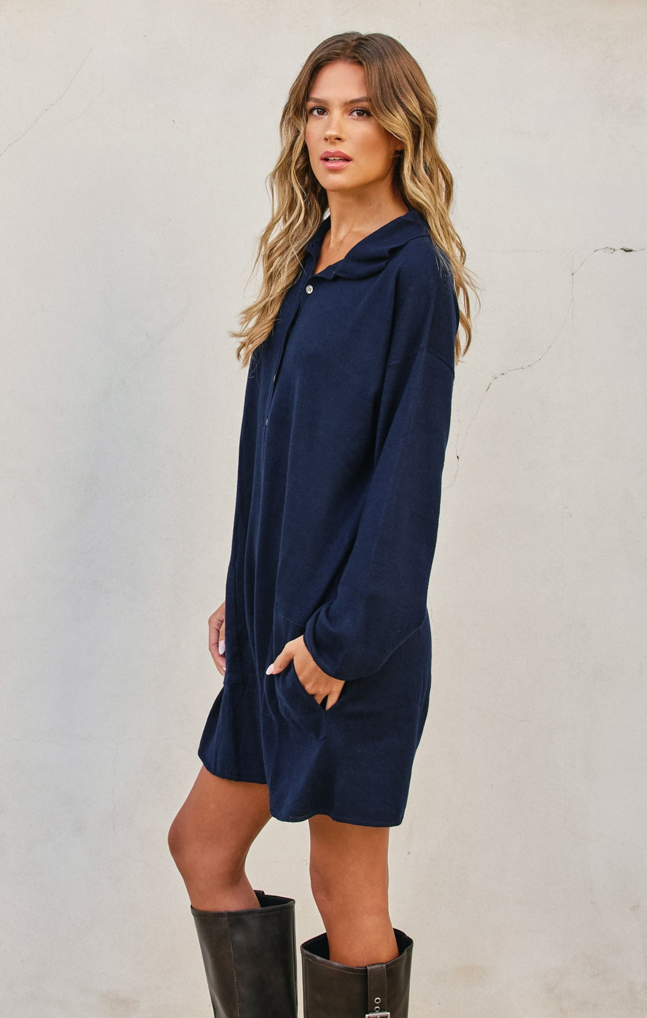 Woman wearing a navy blue dress with long sleeves against a plain background