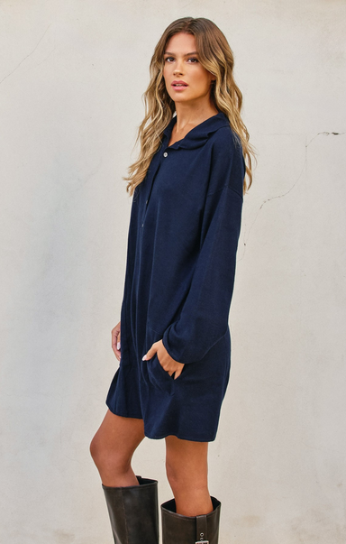 Woman wearing a navy blue dress with long sleeves against a plain background