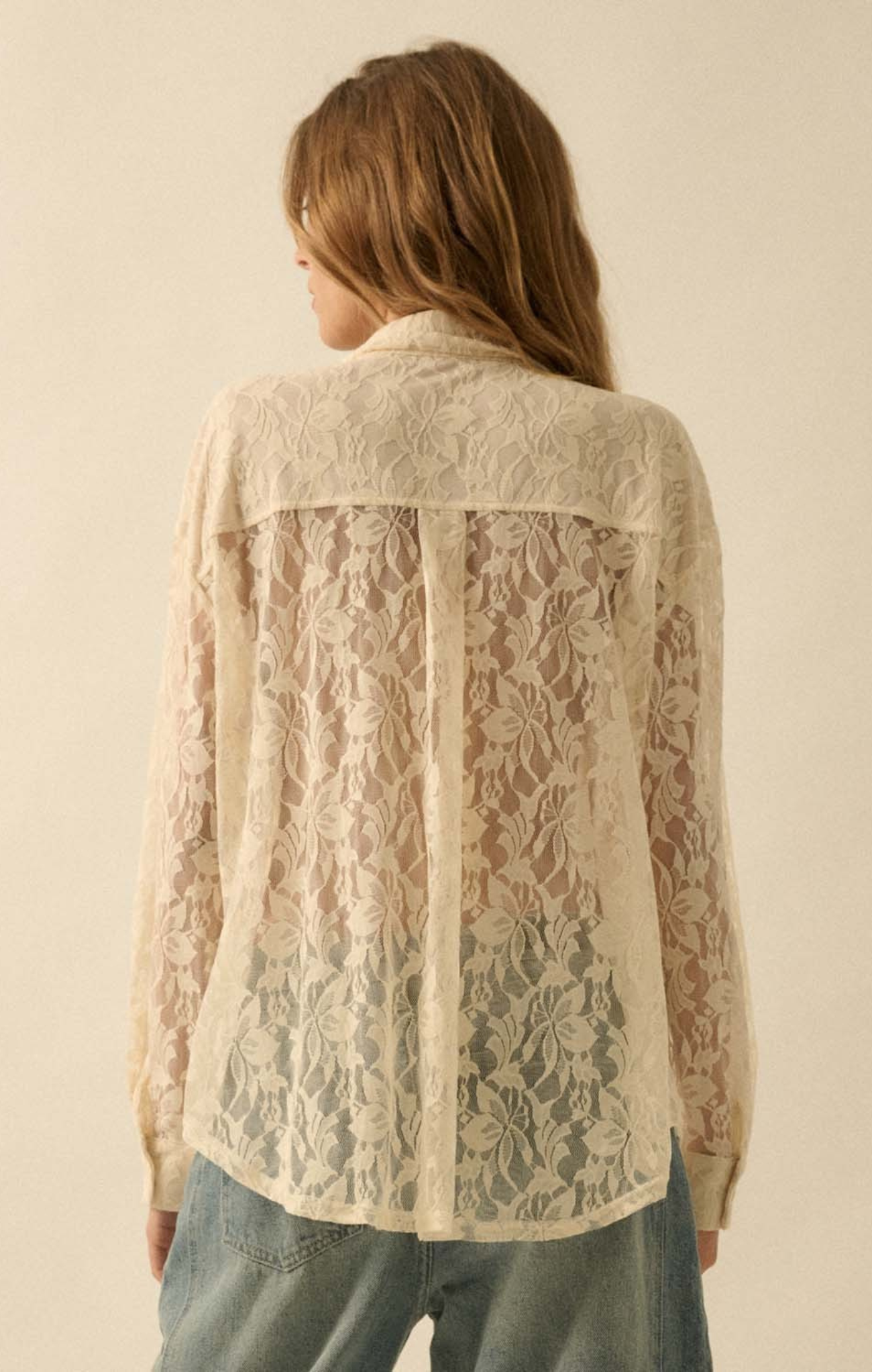 Woman wearing a beige lace blouse against a plain background