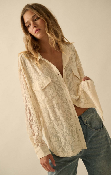 Woman wearing a lace blouse and jeans against a plain background