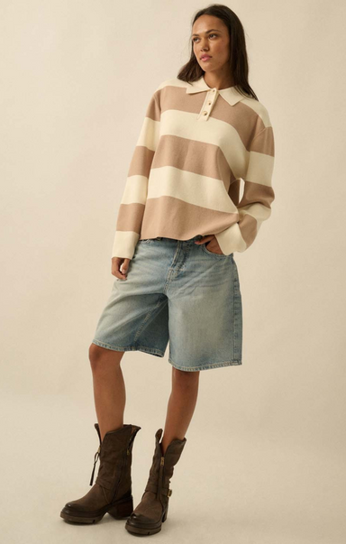 Woman wearing a striped sweater and denim shorts on a beige background
