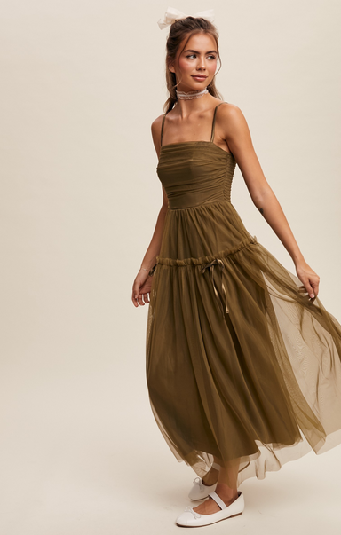 Woman wearing a long brown dress against a plain background