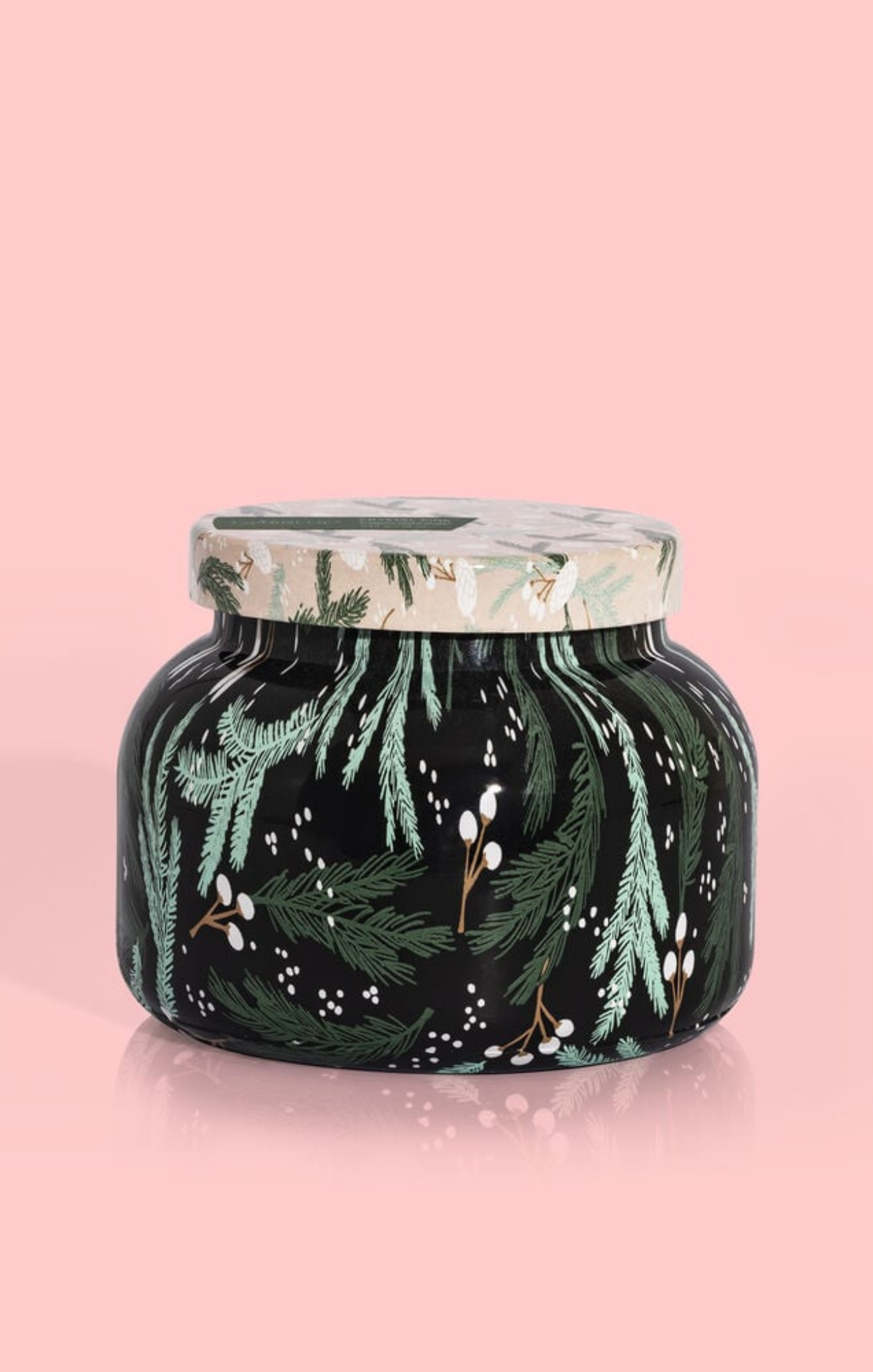 Decorative candle jar with green foliage design on a pink background