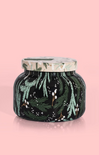 Decorative candle jar with green foliage design on a pink background