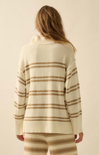 Person wearing a cream and brown striped sweater and pants on a beige background