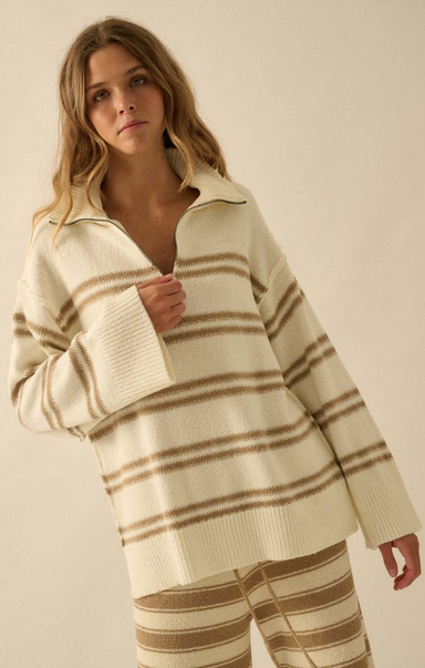 Woman wearing a cream and brown striped sweater and pants on a beige background