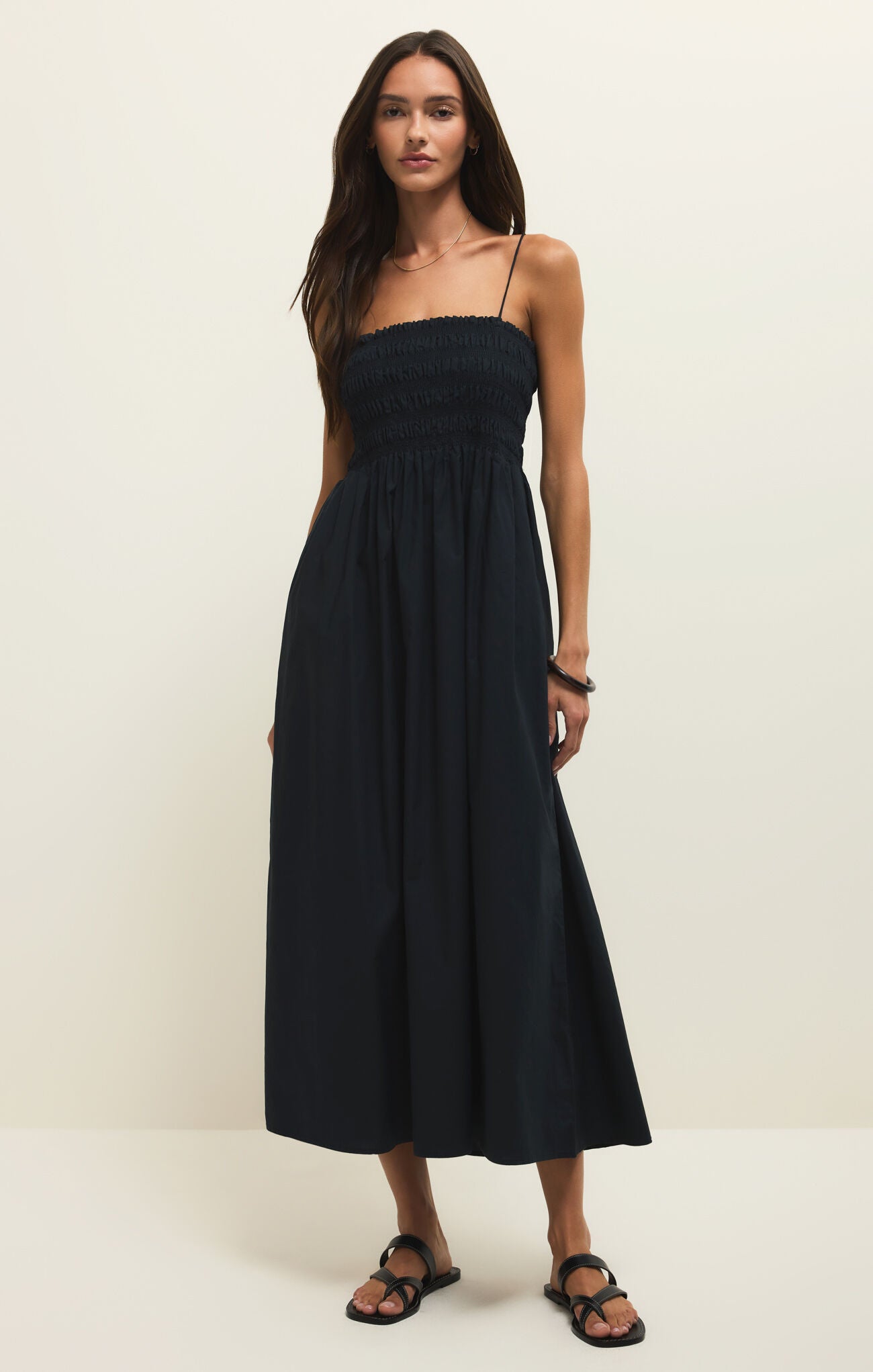 Woman wearing a black strapless dress against a white background