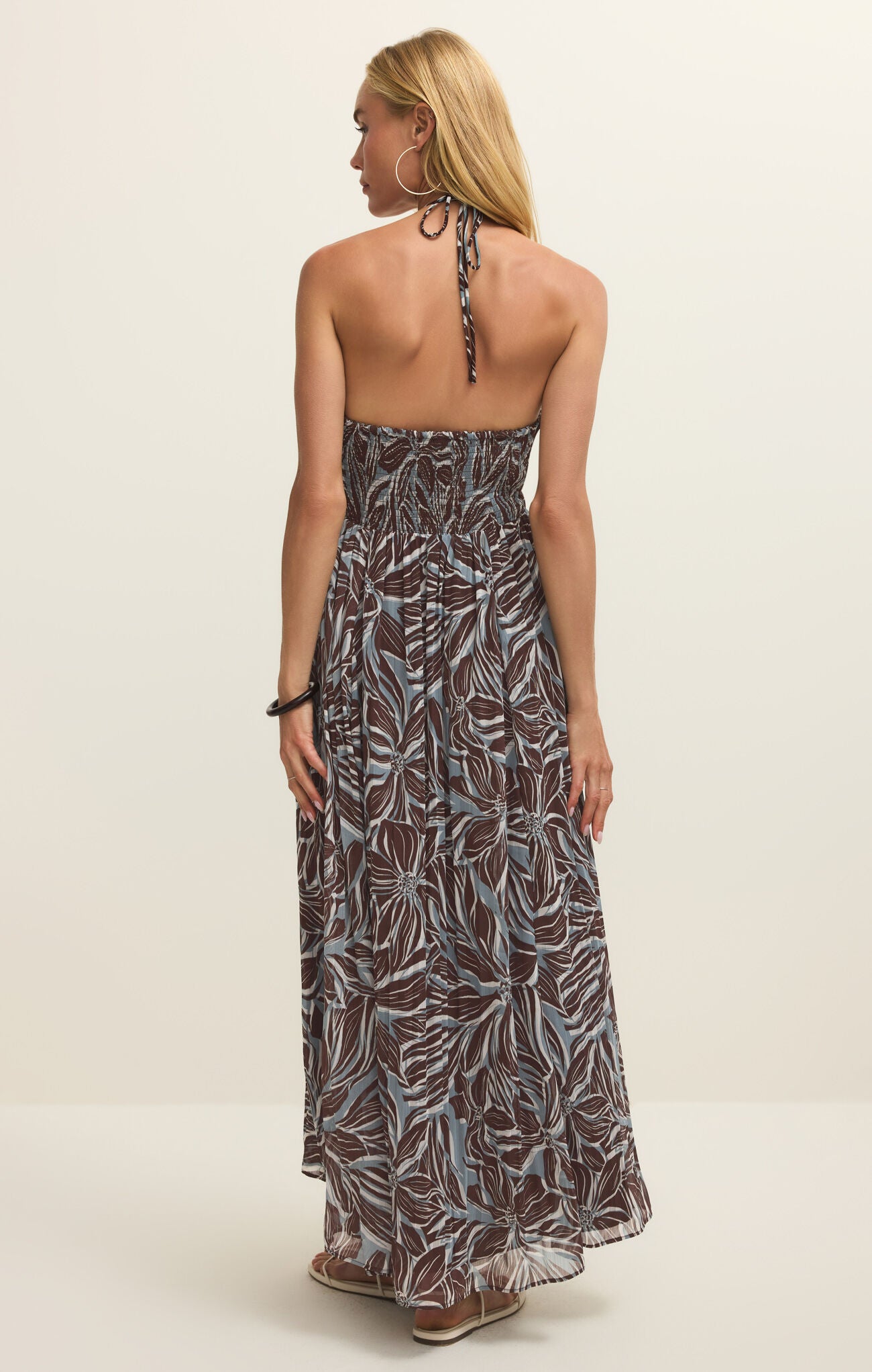 Woman wearing a long, patterned dress on a plain background