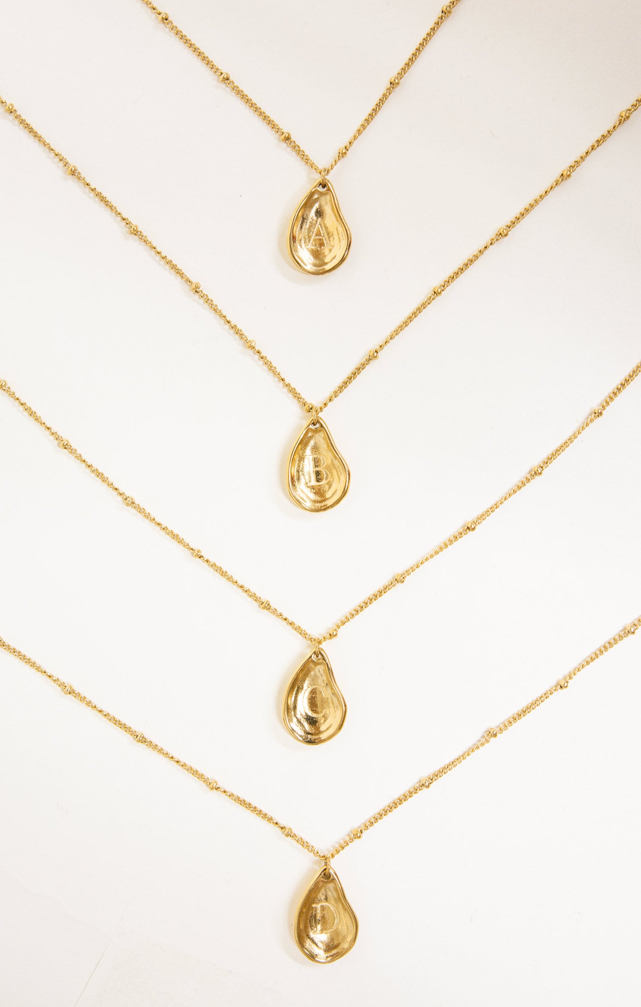 Gold necklaces with teardrop pendants on a white background