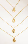 Gold necklaces with teardrop pendants on a white background