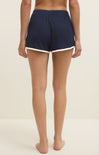 Person wearing navy shorts with white trim on a beige background