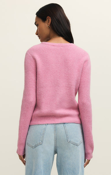 Person wearing a pink sweater and light blue jeans on a beige background