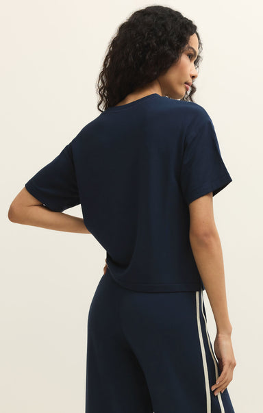 Woman wearing a navy blue outfit against a beige background