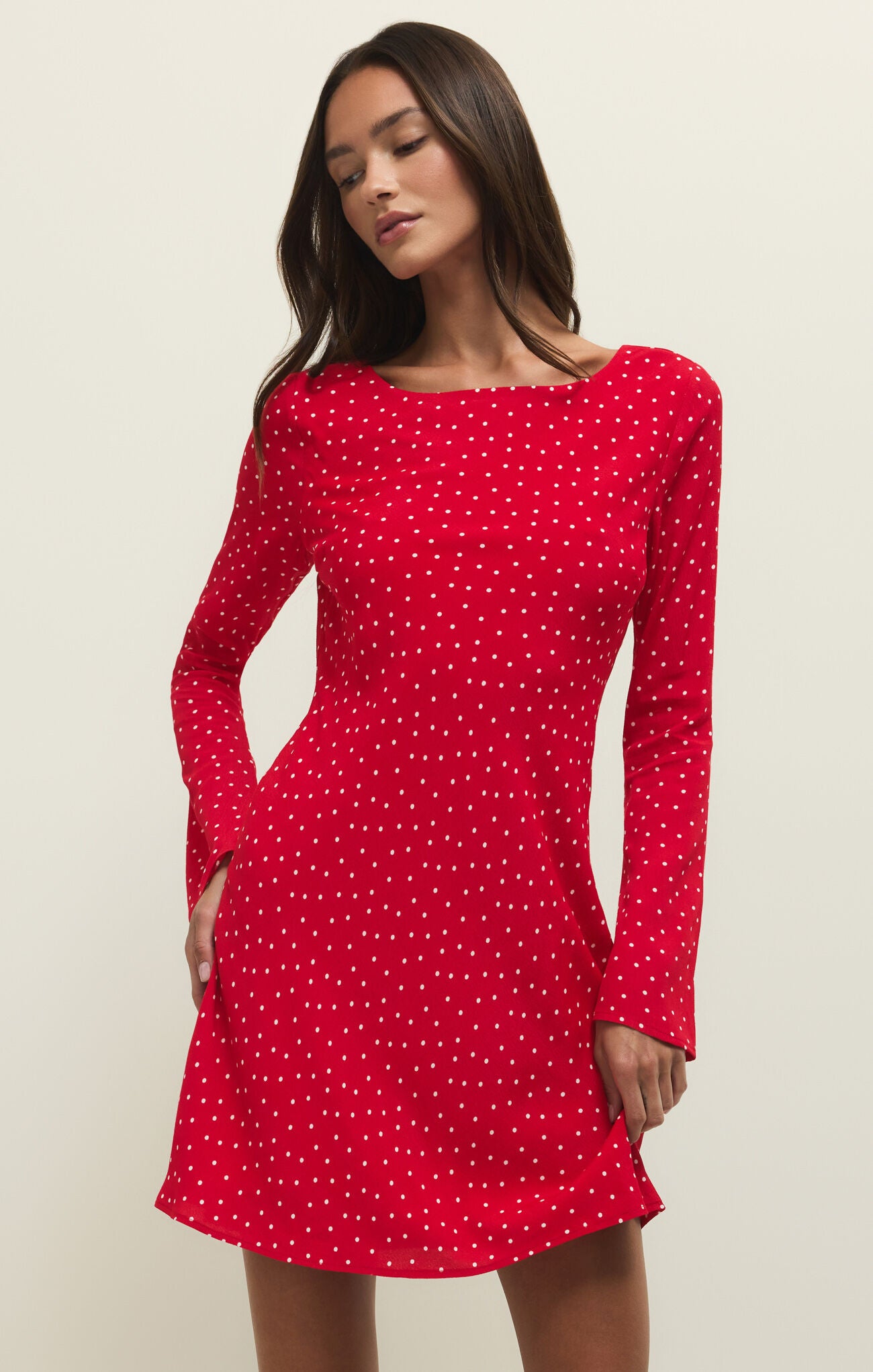 Woman wearing a red polka dot dress against a beige background