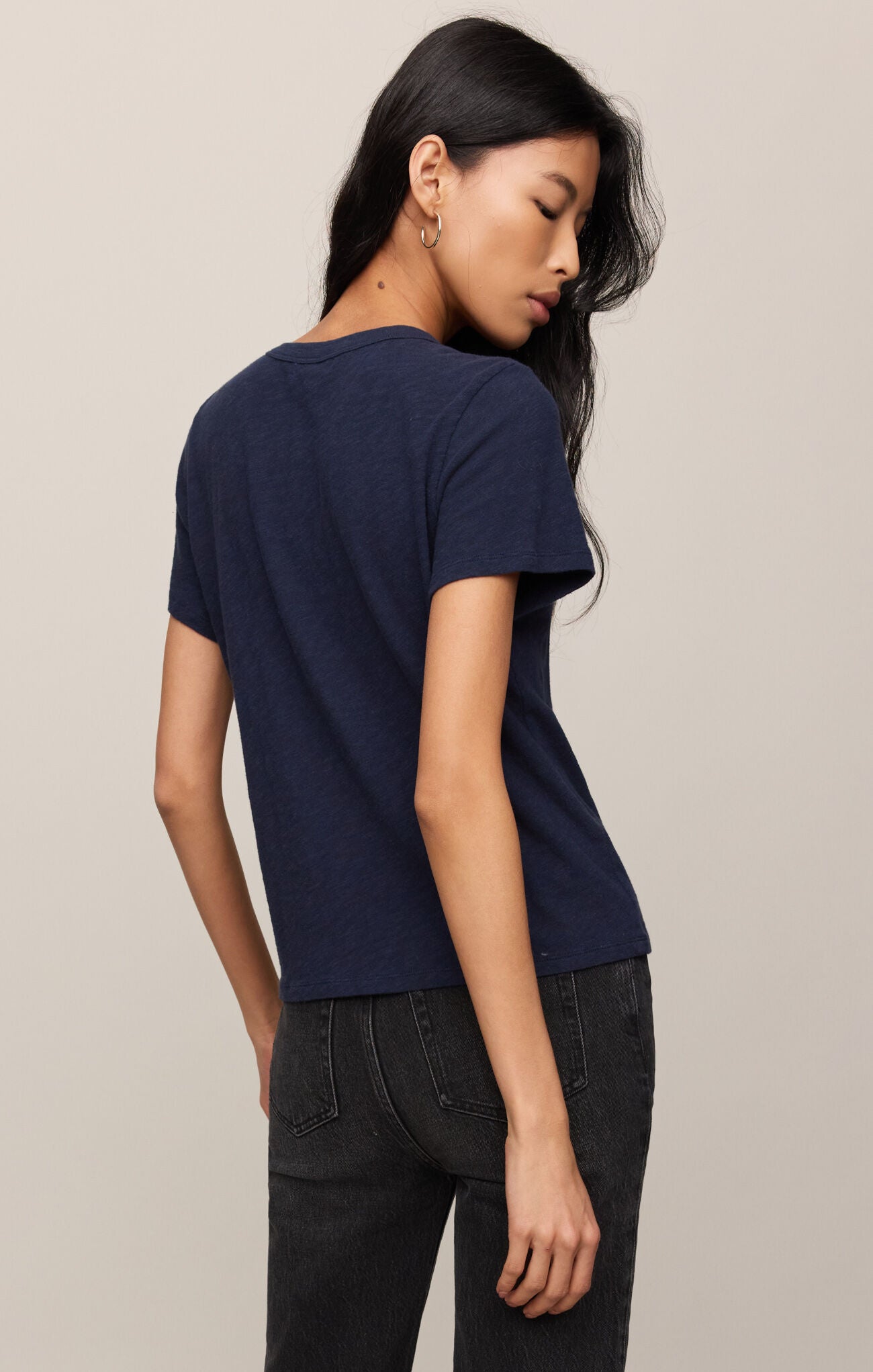Woman wearing a navy blue t-shirt and black pants against a beige background