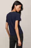 Woman wearing a navy blue t-shirt and black pants against a beige background