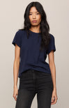 Woman wearing a navy blue t-shirt and black jeans against a beige background