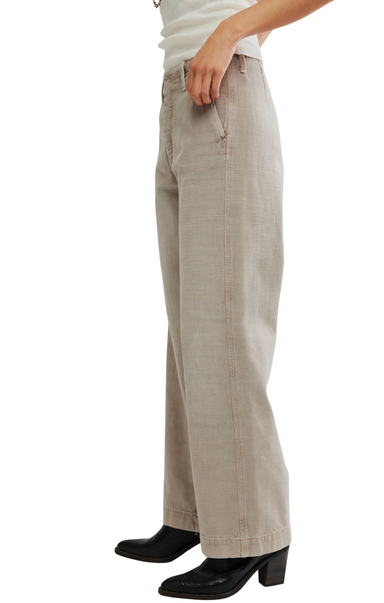 A person wearing light beige wide-leg pants with black heeled boots and a white top, shown from the waist down against a plain white background.