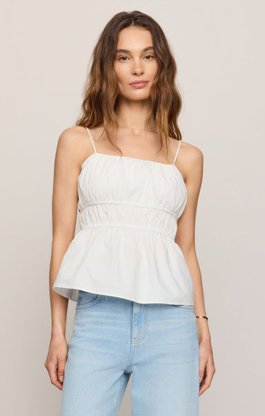 Woman wearing a white top and light blue jeans against a plain background