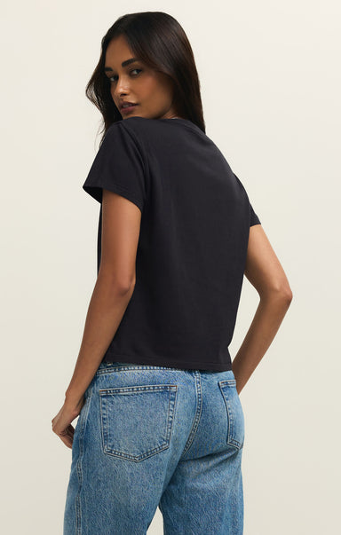 Woman wearing a black t-shirt and blue jeans on a plain background