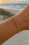 women wearing a gold bracelet at the beach
