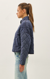 Woman wearing a blue quilted jacket and light blue jeans on a white background