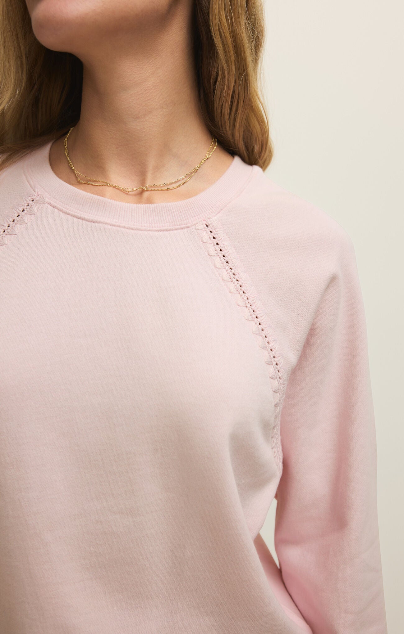 Pink sweater with decorative stitching on a plain background