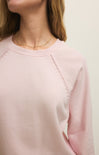 Pink sweater with decorative stitching on a plain background