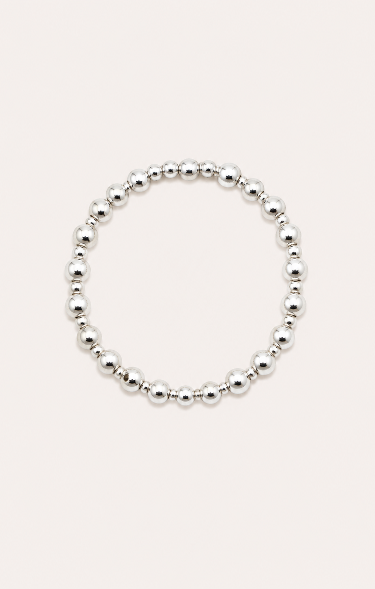 Silver beaded bracelet on a wrist with a beach background