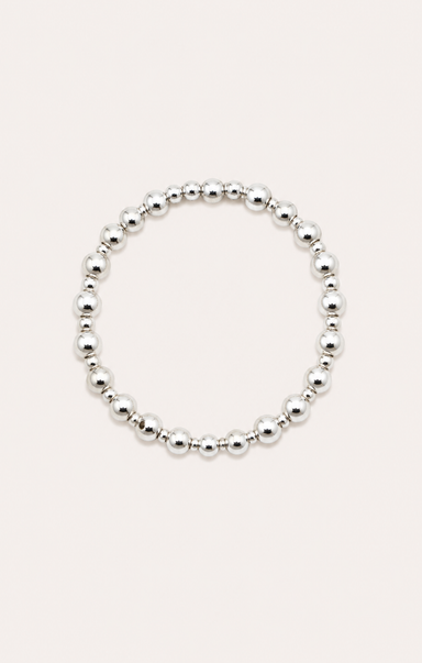 Silver beaded bracelet on a wrist with a beach background