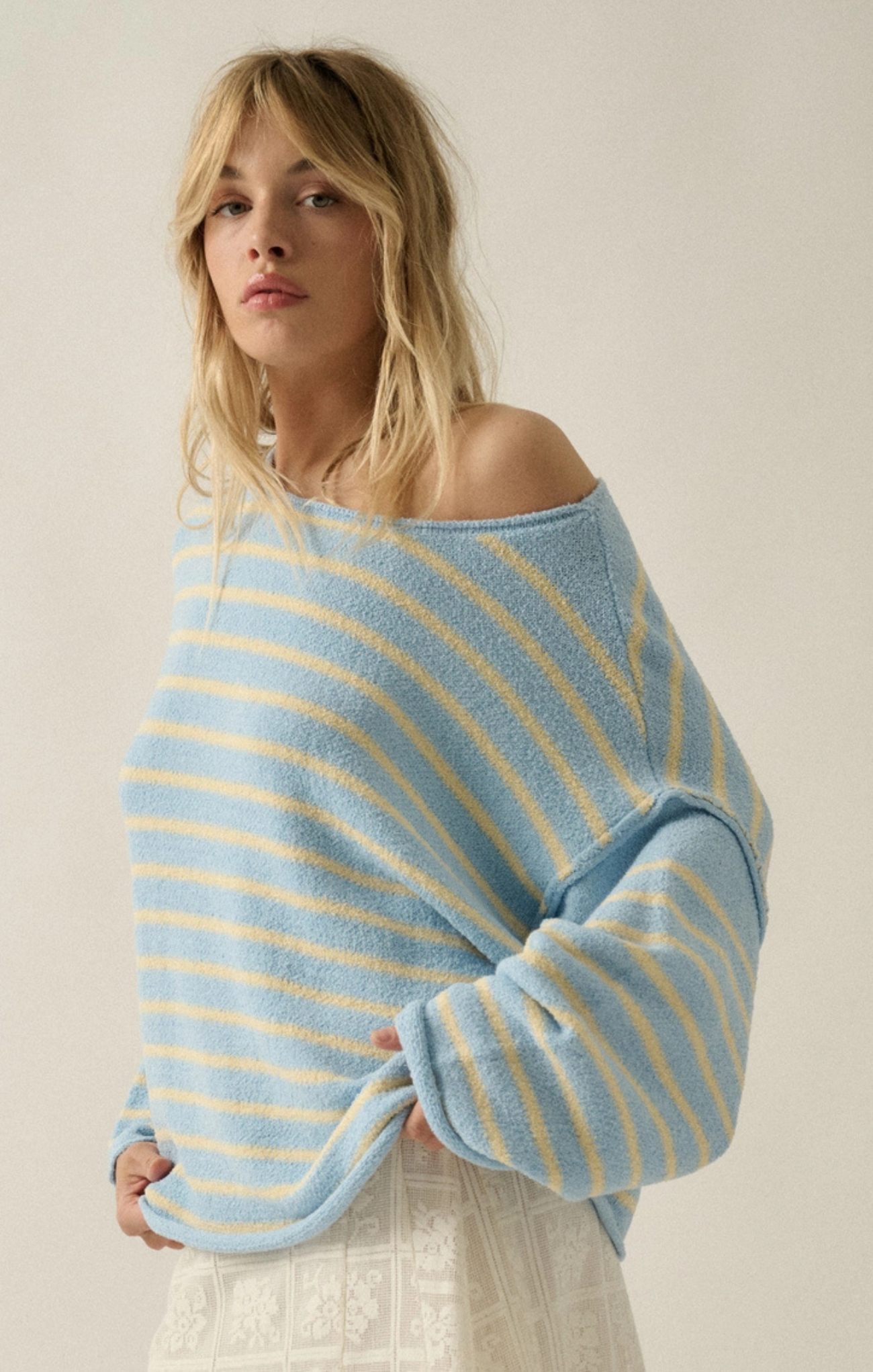 Woman wearing a blue and yellow striped sweater against a plain background