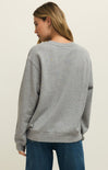 Woman wearing a gray sweatshirt and blue jeans on a beige background