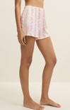 Person wearing pink floral shorts on a beige background