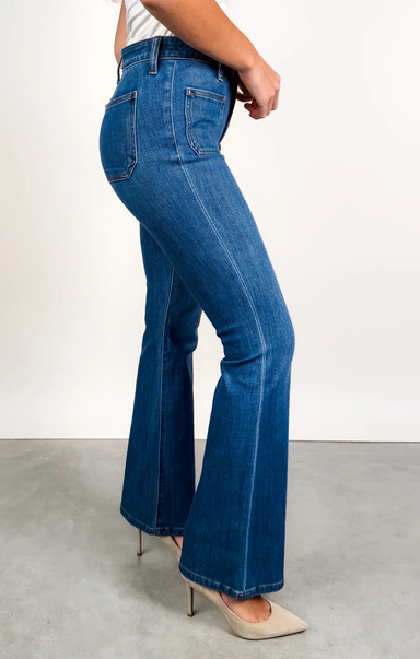 Person wearing blue flared jeans on a plain background