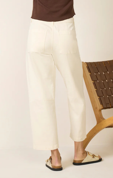 Person wearing white pants and a brown top on a plain background