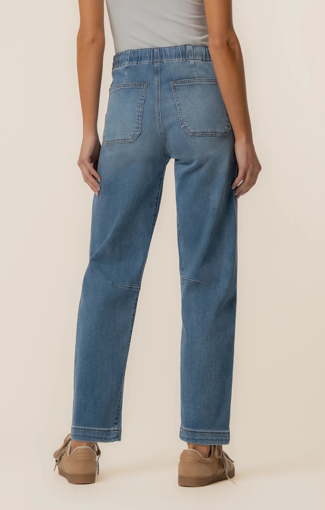 Person wearing blue jeans on a plain background