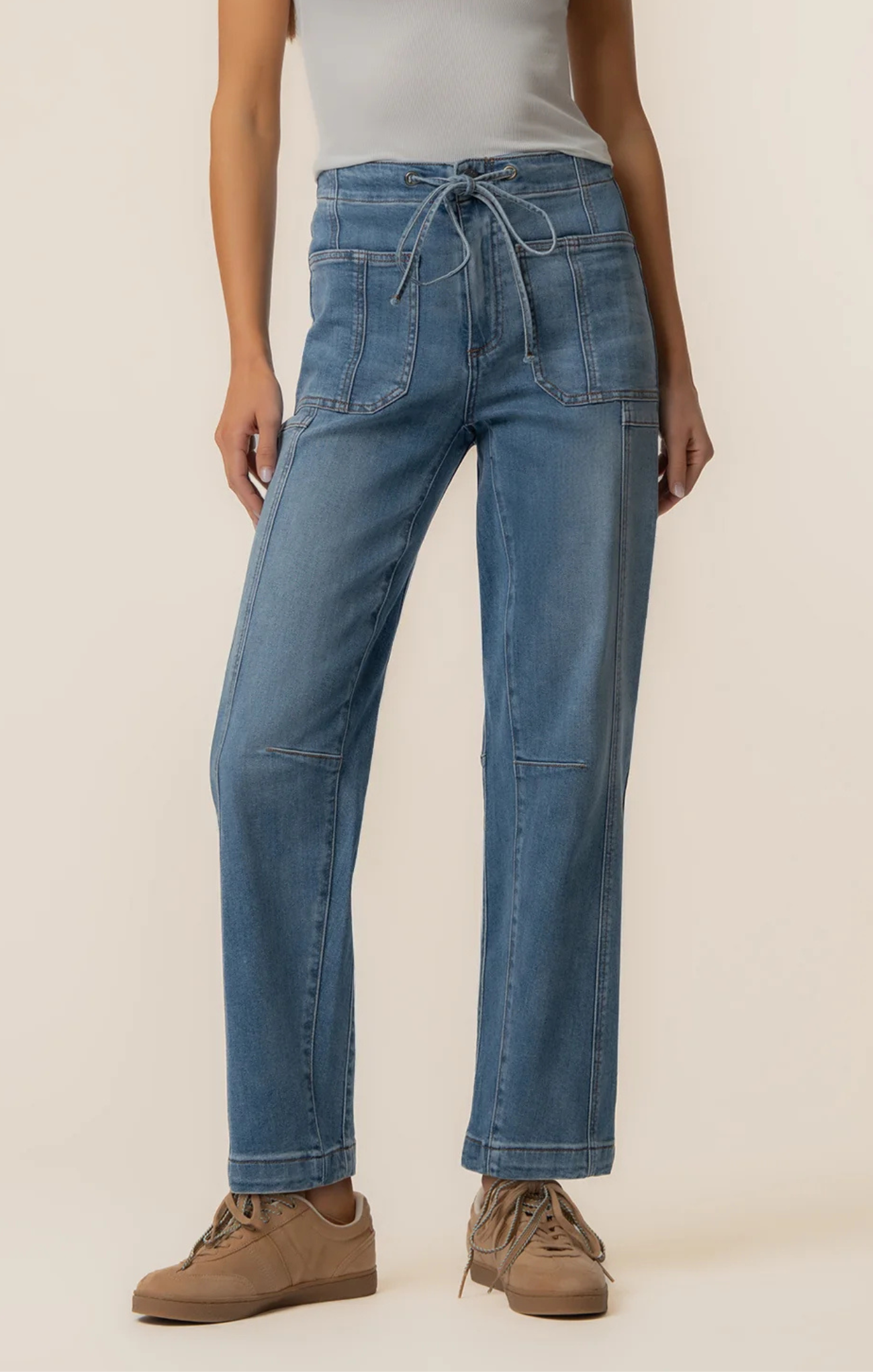 Person wearing blue jeans and brown shoes on a beige background