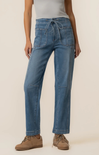 Person wearing blue jeans and brown shoes on a beige background