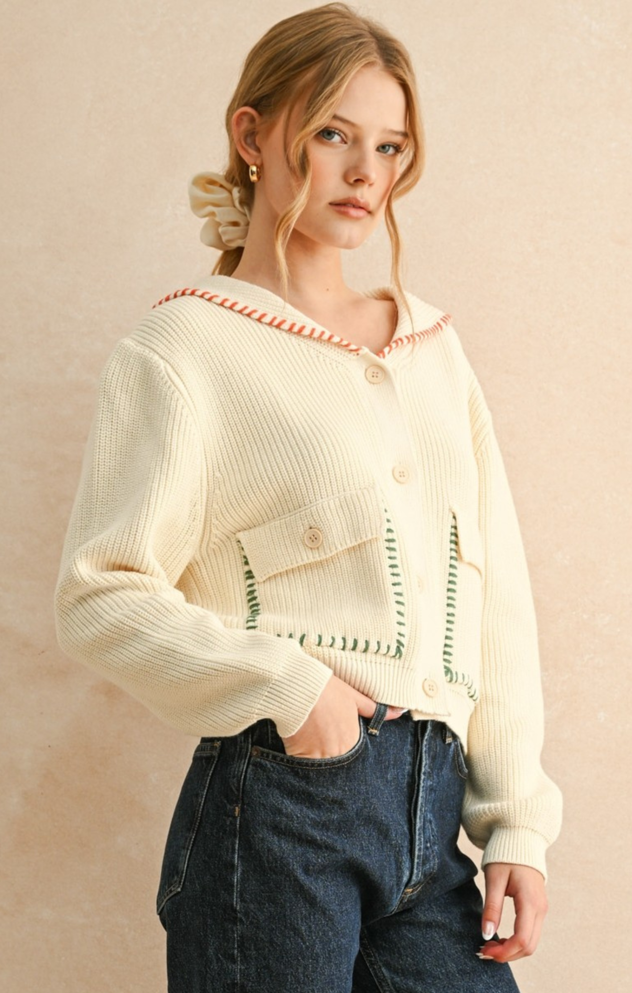 Woman wearing a cream-colored knit cardigan with a beige background