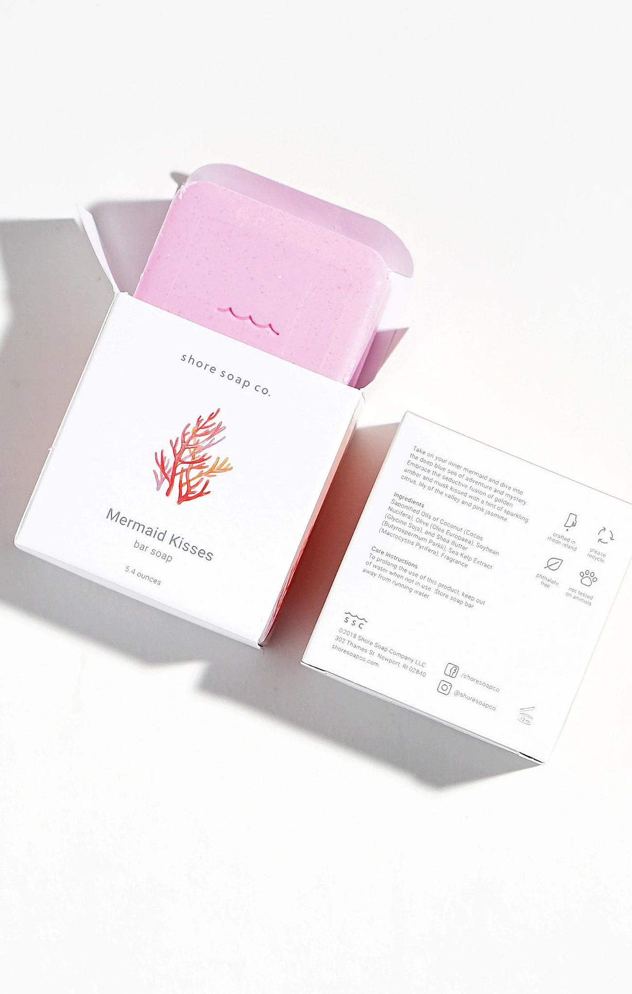 Pink soap bar with packaging and label on a white background